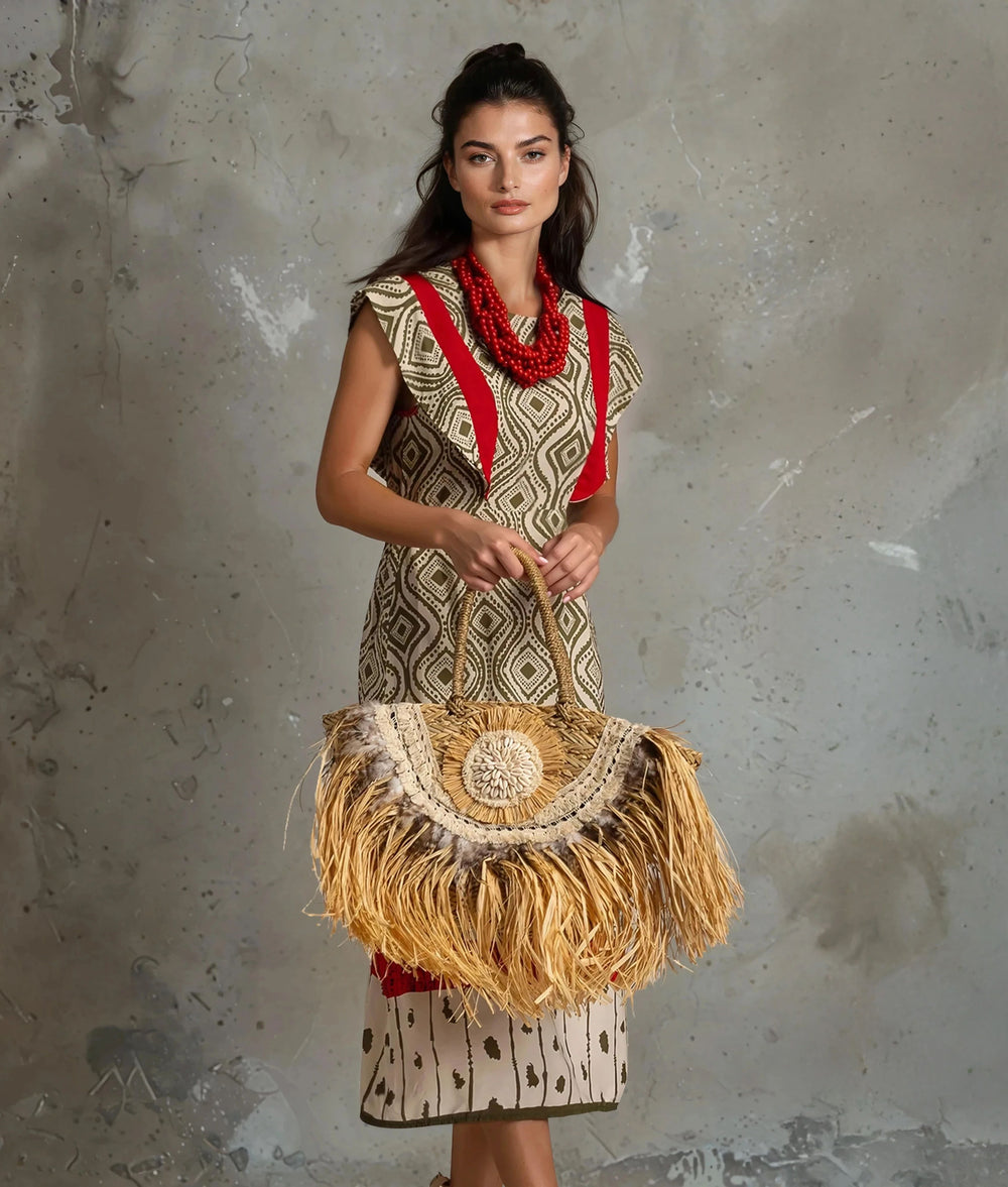 Model wearing patterned midi dress with red details and straw handbag – front view