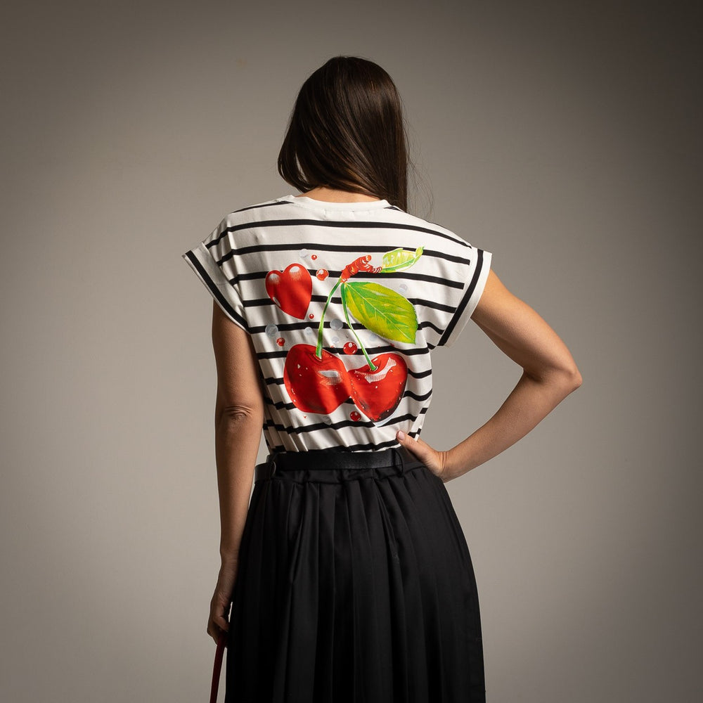 Back view of a black and white striped T-shirt with a large cherry and heart print, paired with a black pleated skirt, white base version.