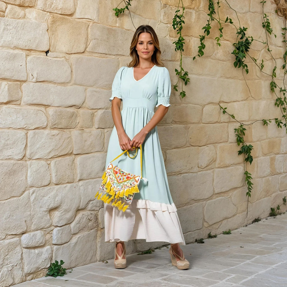 Woman wearing mint and off-white midi dress with v-neck and yellow embroidered handbag