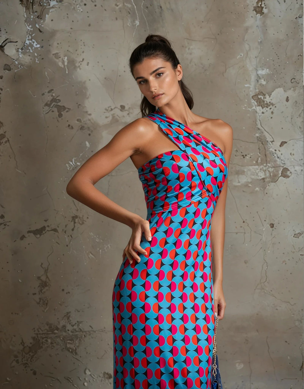 Detail shot of geometric print on the dress with crossover strap and fitted waist, styled with a blue handbag