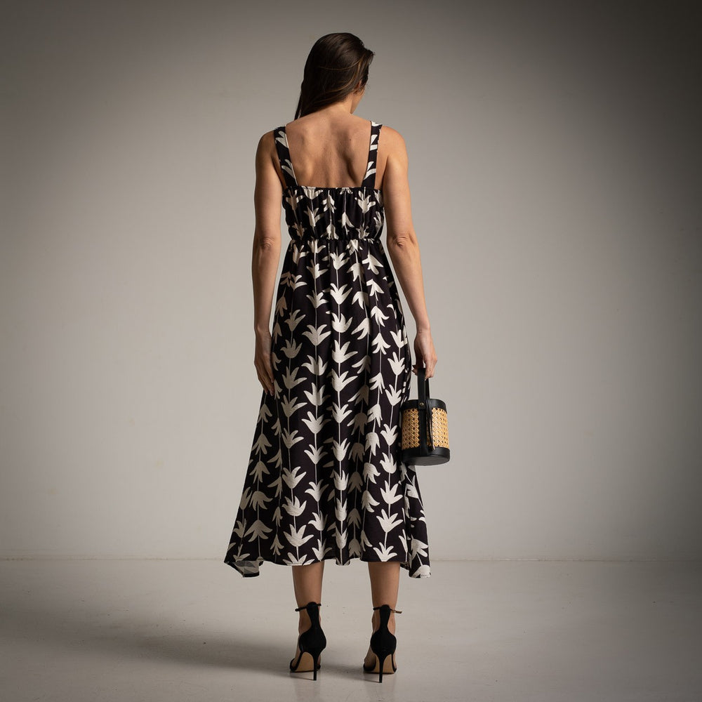 Back view of black leaf print dress with elastic gathered waist and wide straps