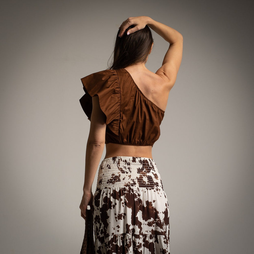 Back view of brown ruffle one shoulder crop top with printed high-waisted maxi skirt