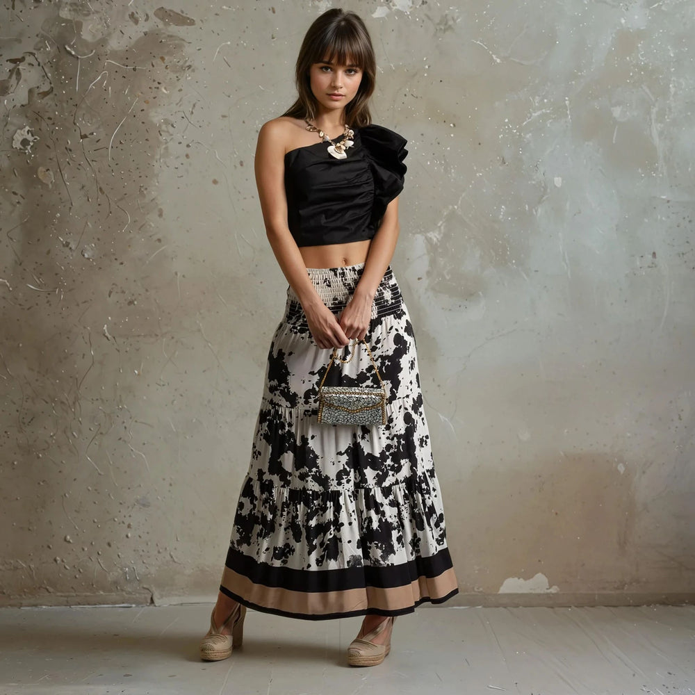 Model wearing abstract animal print maxi skirt in black and beige with wide smocked waistband and crop top.