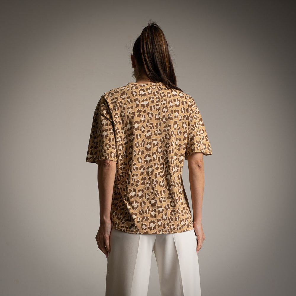 Back view of woman wearing oversized leopard print shirt with white trousers