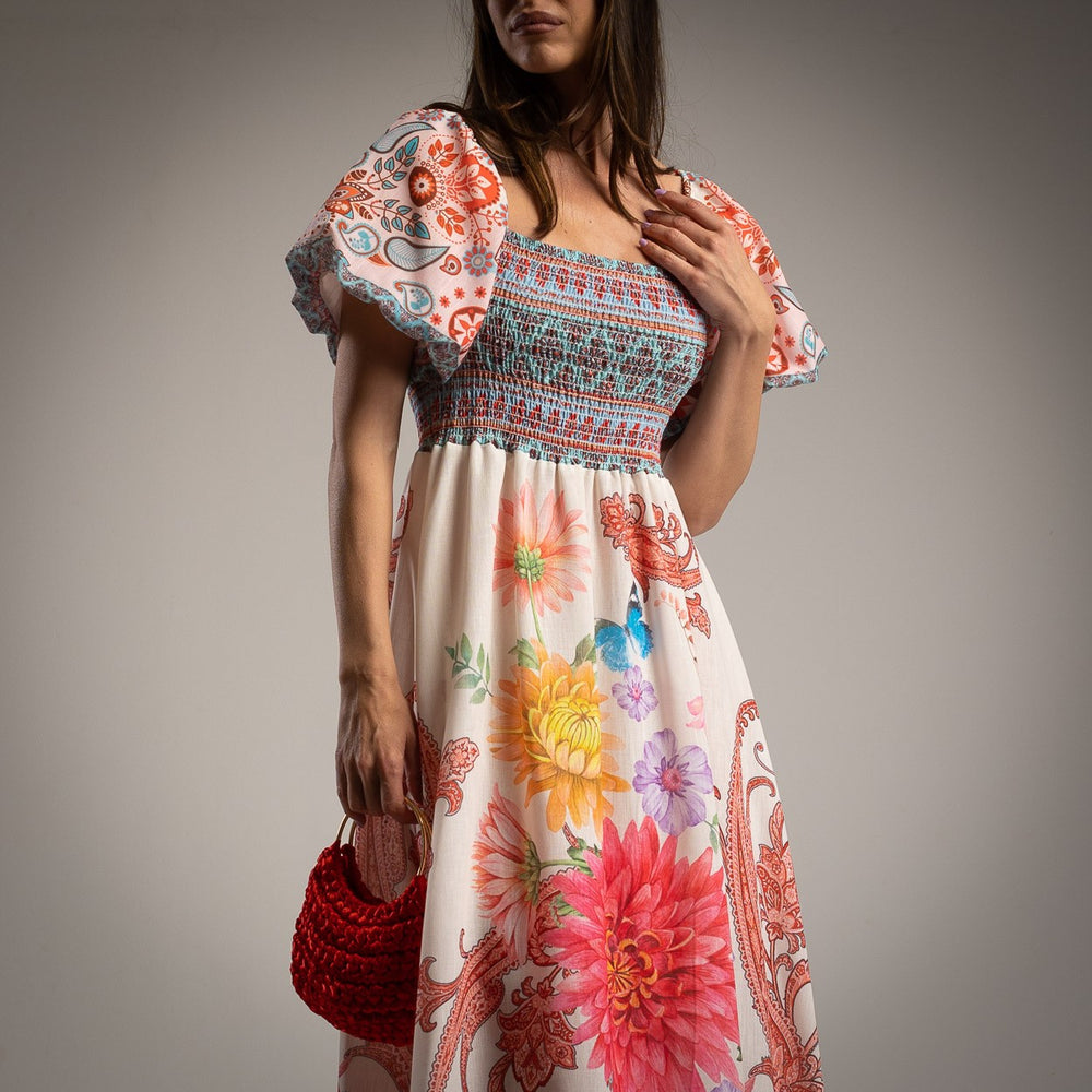 Close-up of the smocked bodice and puff sleeves of a vibrant floral-print midi dress, highlighting the detailed pattern and fabric texture.