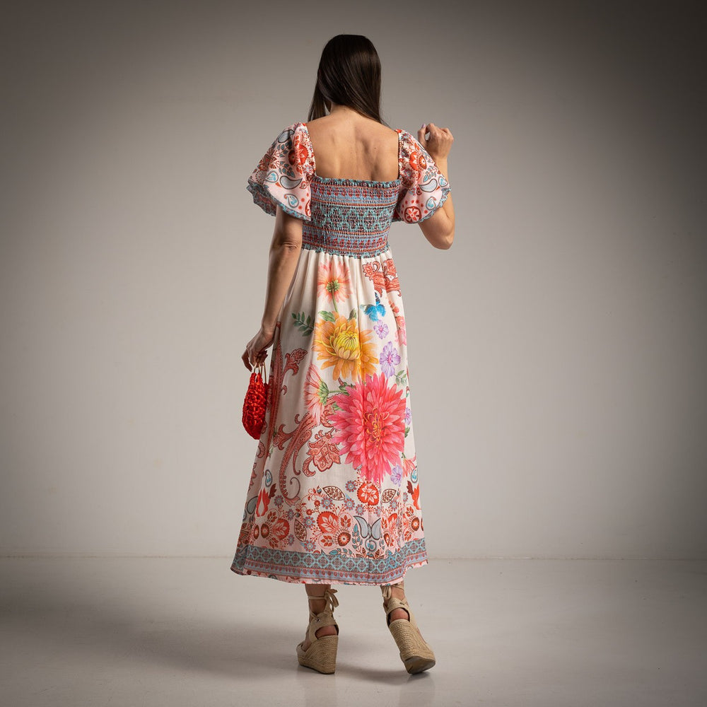 Back view of a bohemian-style floral dress with a smocked top and flowy skirt with a neutral background