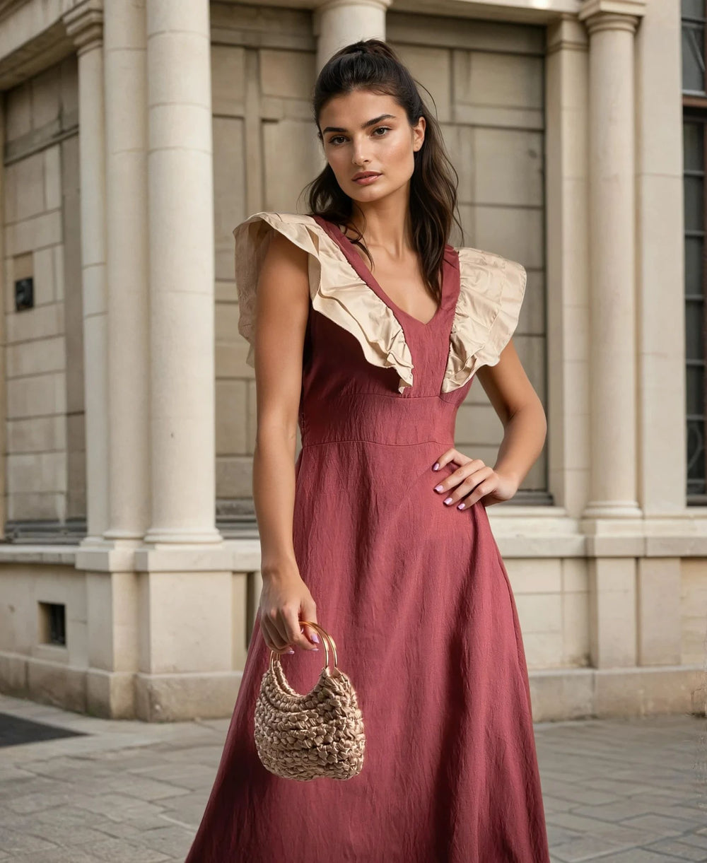 Close-up of a rust-red dress with beige ruffle-trimmed neckline, showing the fabric texture and feminine shoulder detailing.