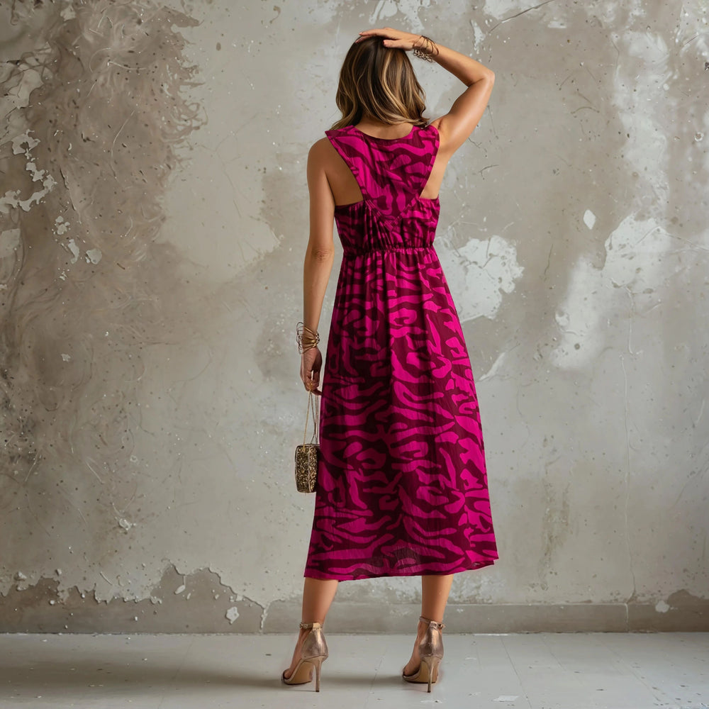 Rear view of a pink and magenta printed dress with a relaxed fit and open-back detail, worn with gold heels.