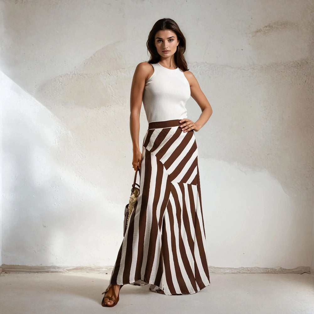 Model wearing brown striped maxi skirt with ribbed white tank top and straw bag