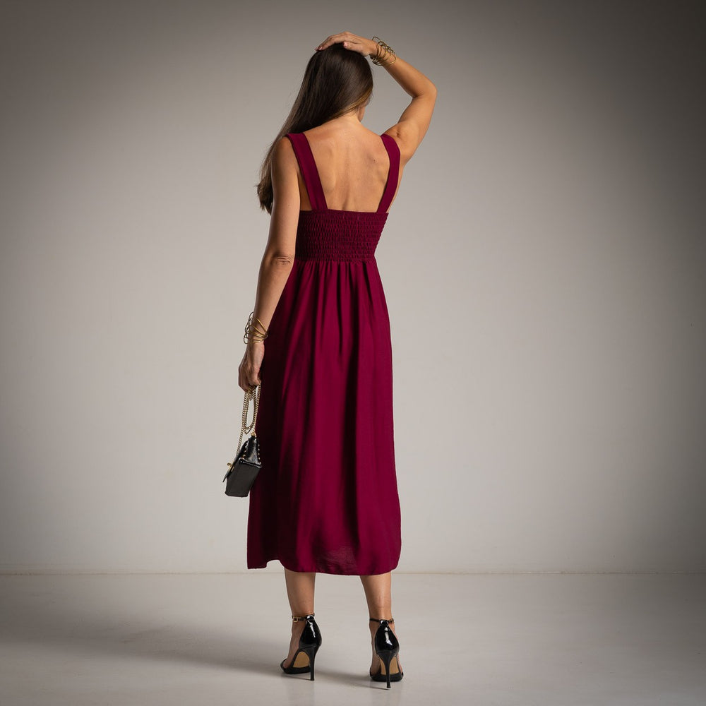 Back view of MARIΓIOÚ elegant burgundy midi dress with smocked fit and flowing skirt