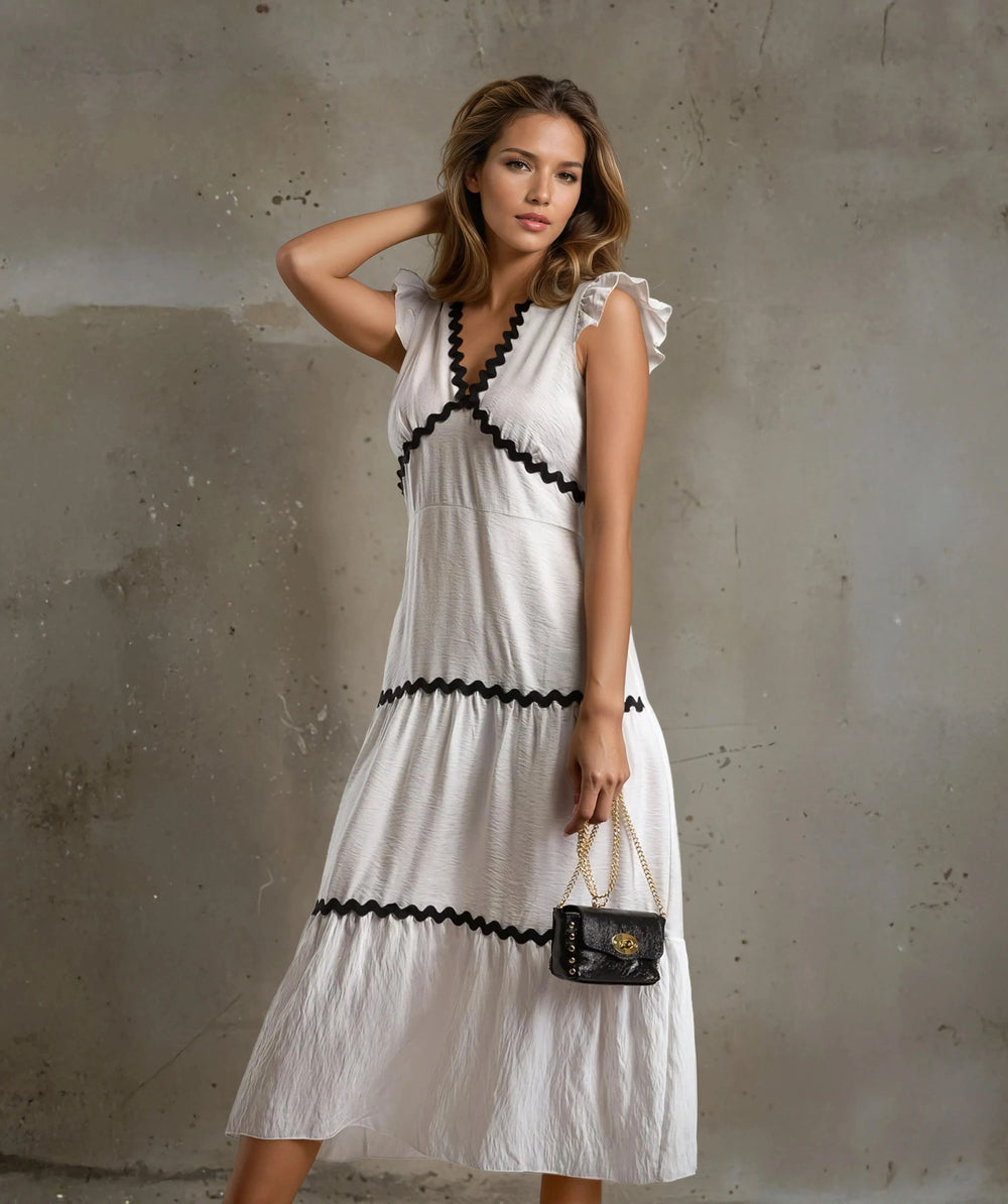 Front view of white midi dress with black zigzag trim and ruffled sleeves