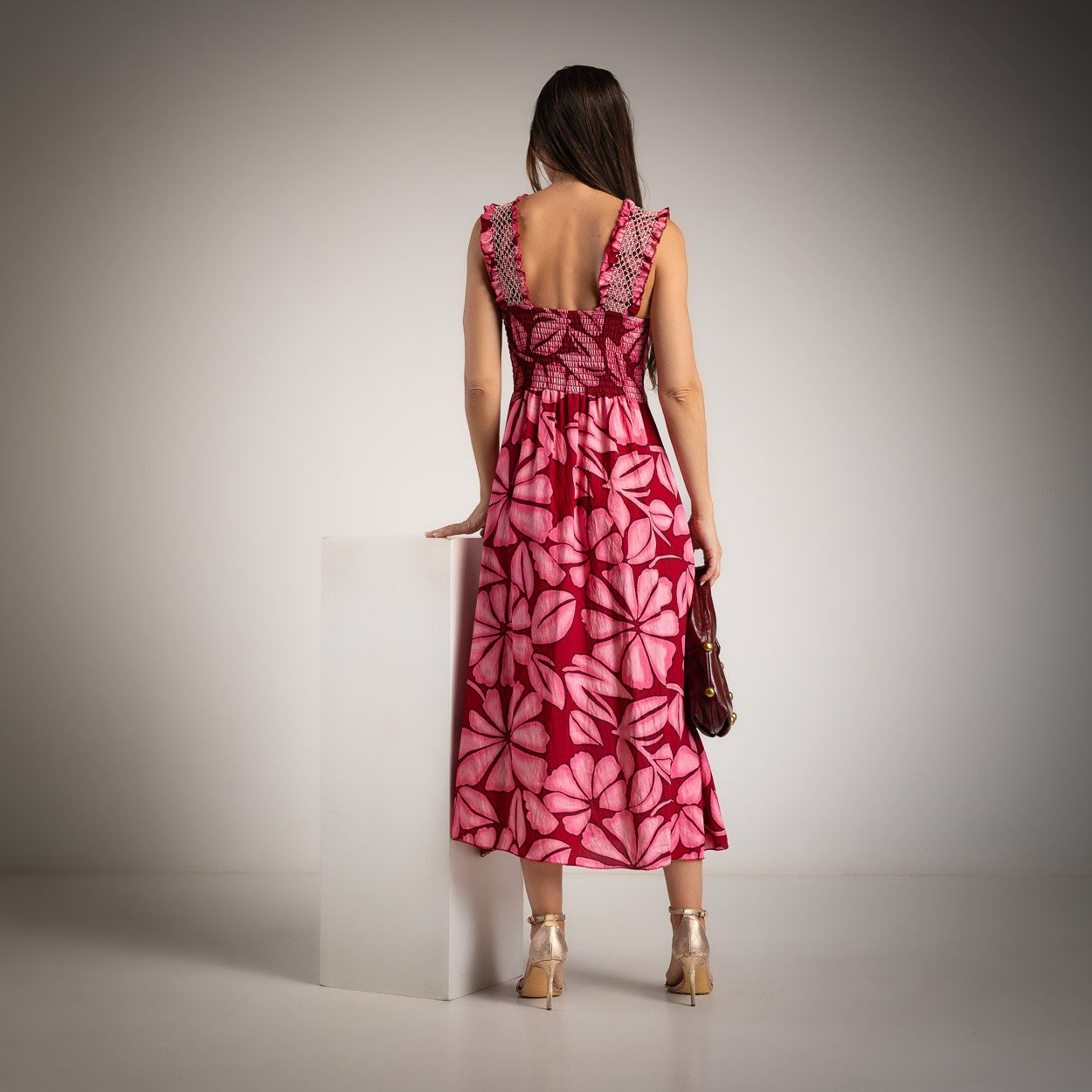 Back view of a pink floral midi dress featuring ruffle straps and a smocked elastic back