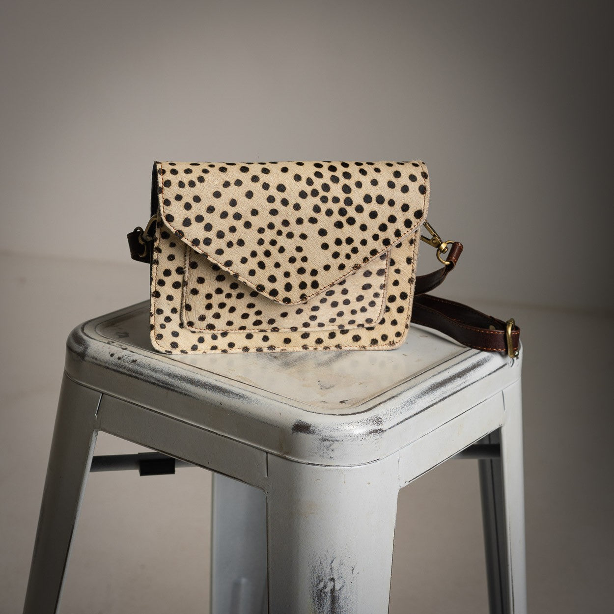 Spotted leather crossbody bag with flap closure and adjustable strap