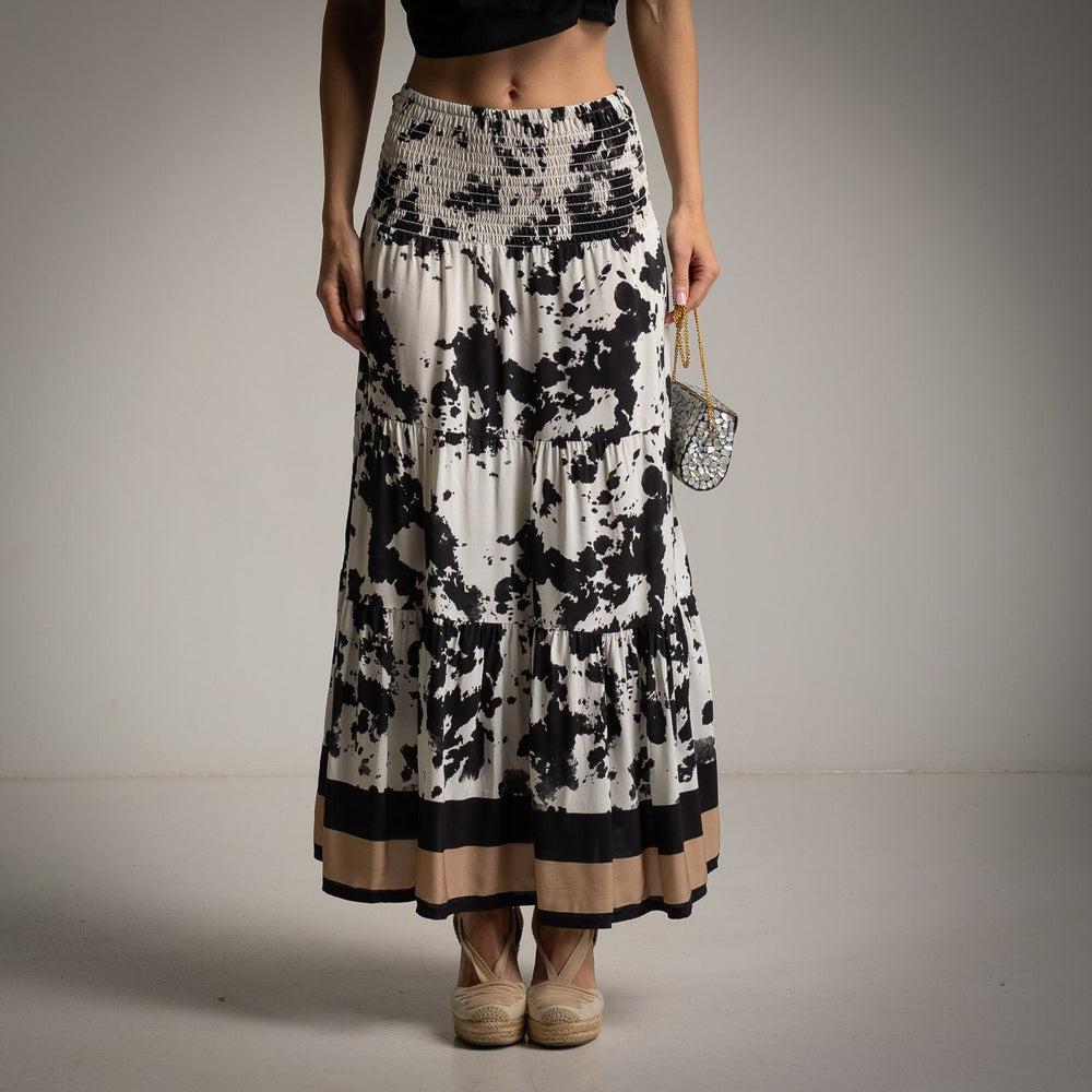 Close-up front view of maxi skirt with black abstract print and beige hemline.