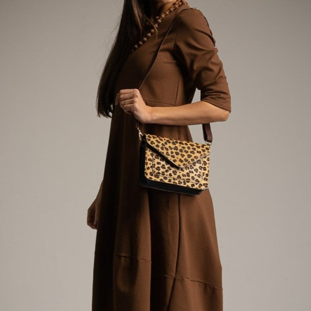 Cheetah leather crossbody bag worn with brown dress