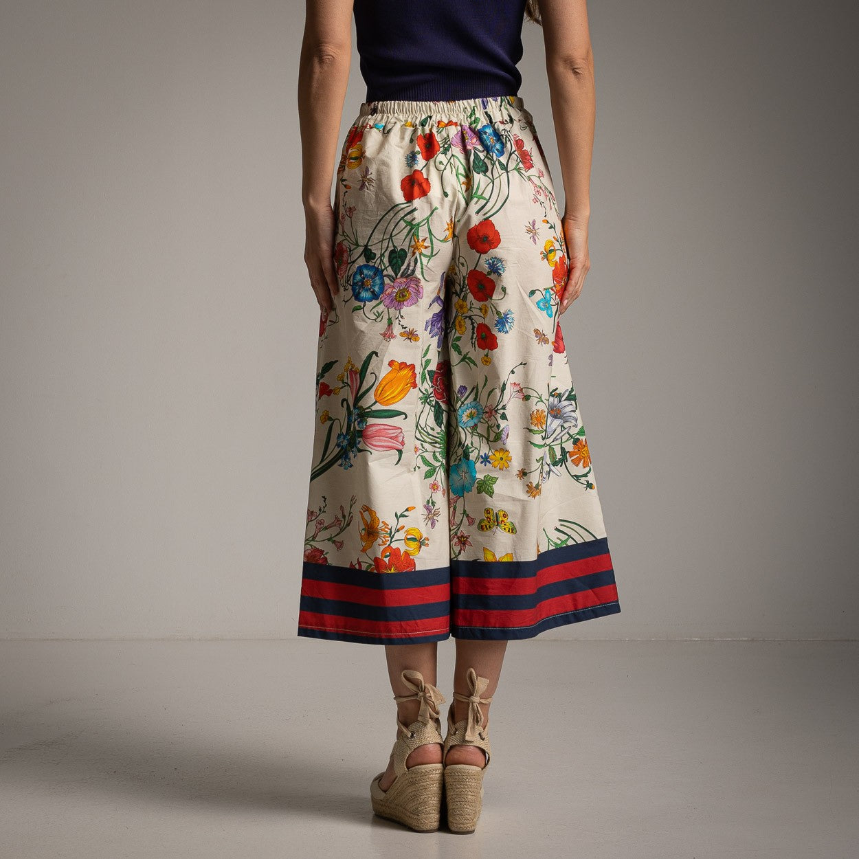 Back view of floral cotton culotte pants in Ivory White with an elastic waistband and colorful floral design.