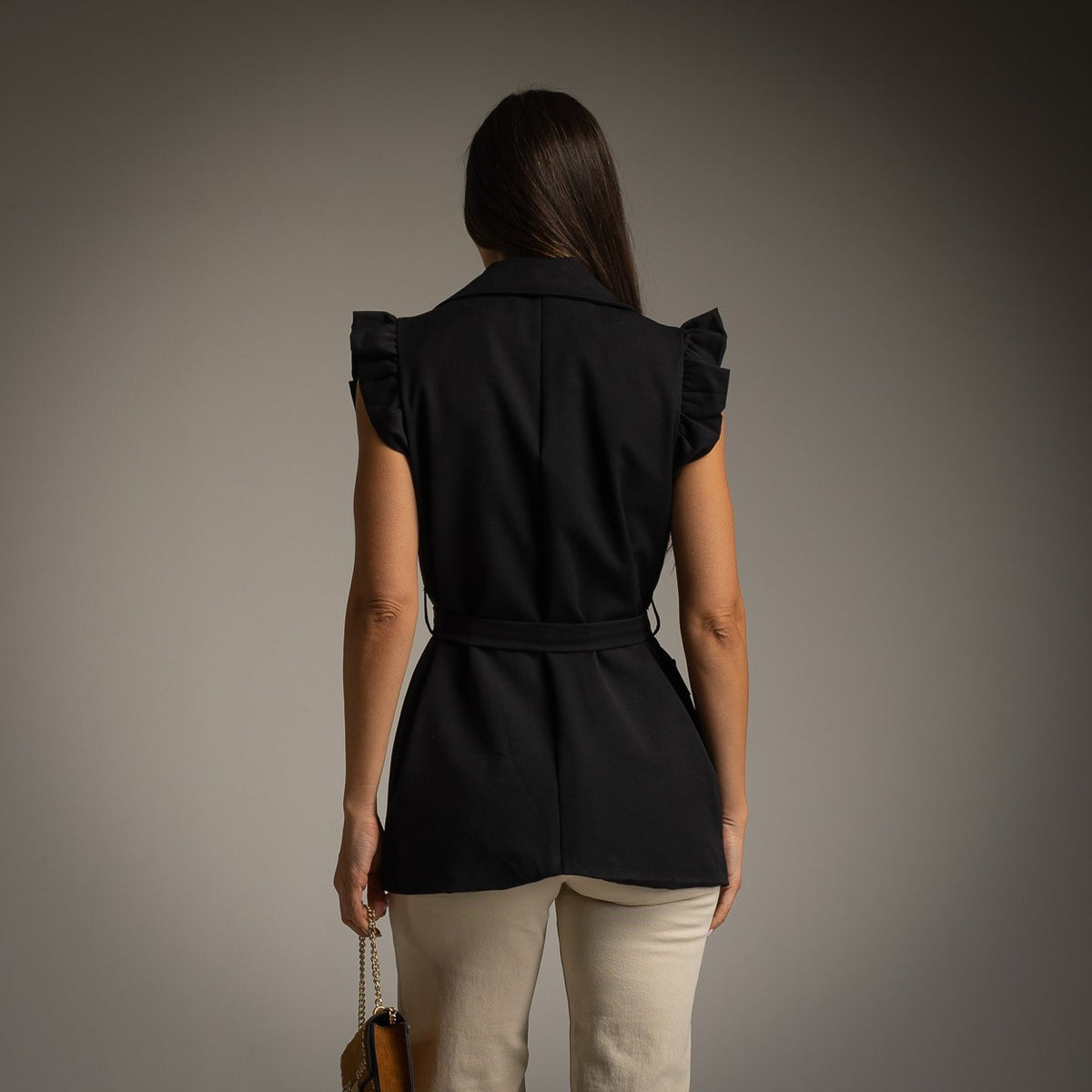Black sleeveless belted vest with lapel collar and ruffled cap sleeves - back view