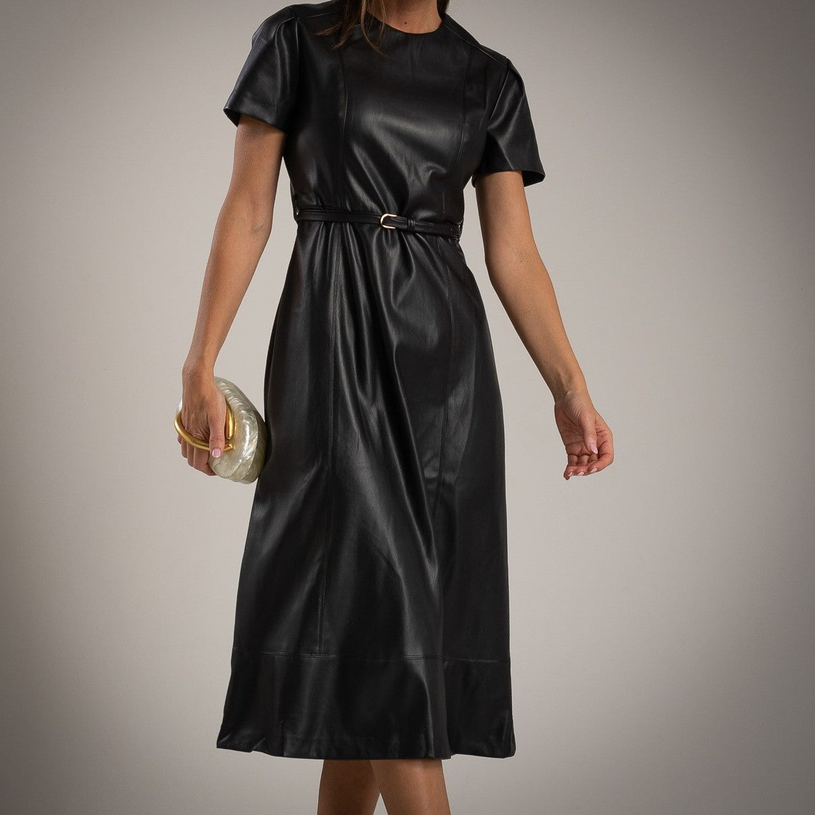 Close-up of MARIΓIOÚ black faux leather midi dress with short sleeves and slim belt – chic vegan leather outfit.