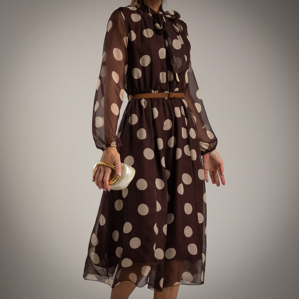 Model wearing MARIΓIOÚ brown polka dot midi dress with bow tie neck and belt – elegant fall outfit made in Italy.