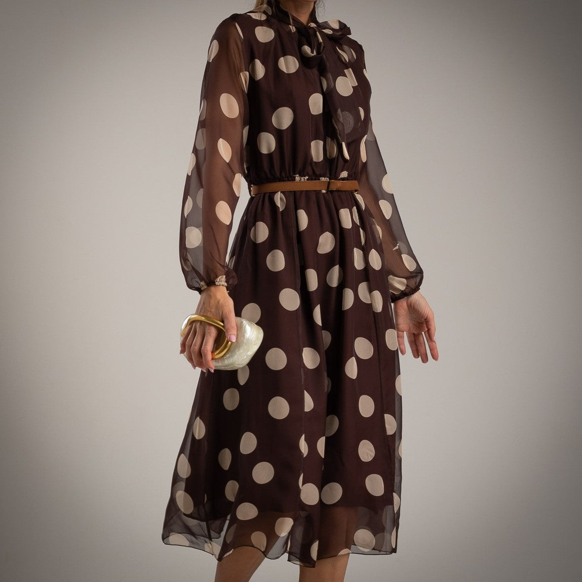 Model wearing MARIΓIOÚ brown polka dot midi dress with bow tie neck and belt – elegant fall outfit made in Italy.