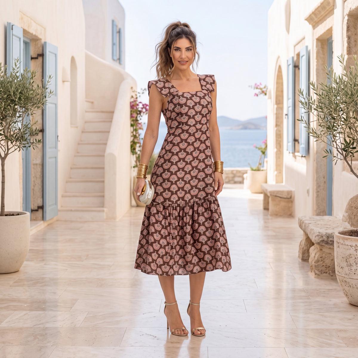 Woman wearing a chocolate brown fan print midi dress with square neckline in a Mediterranean seaside setting