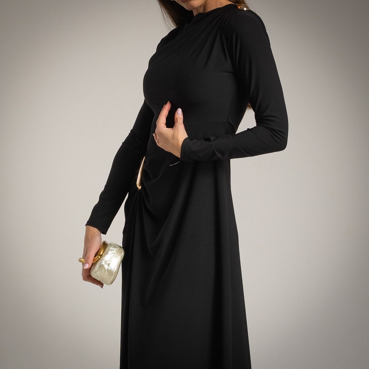 Detail view of black draped midi dress with gold accent