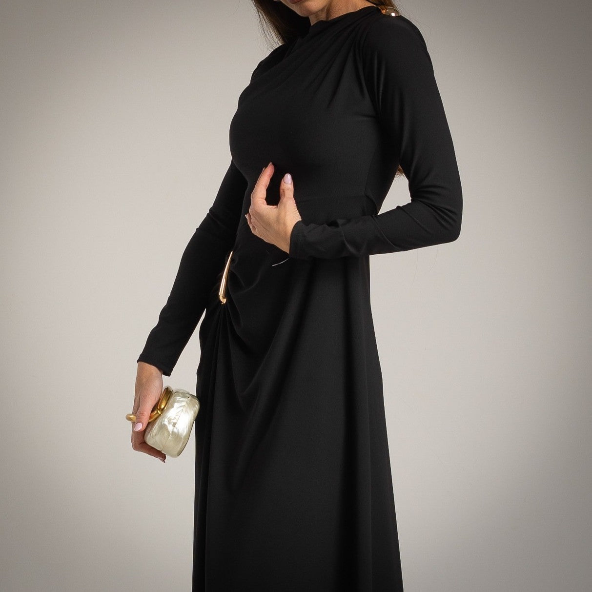 Detail view of black draped midi dress with gold accent