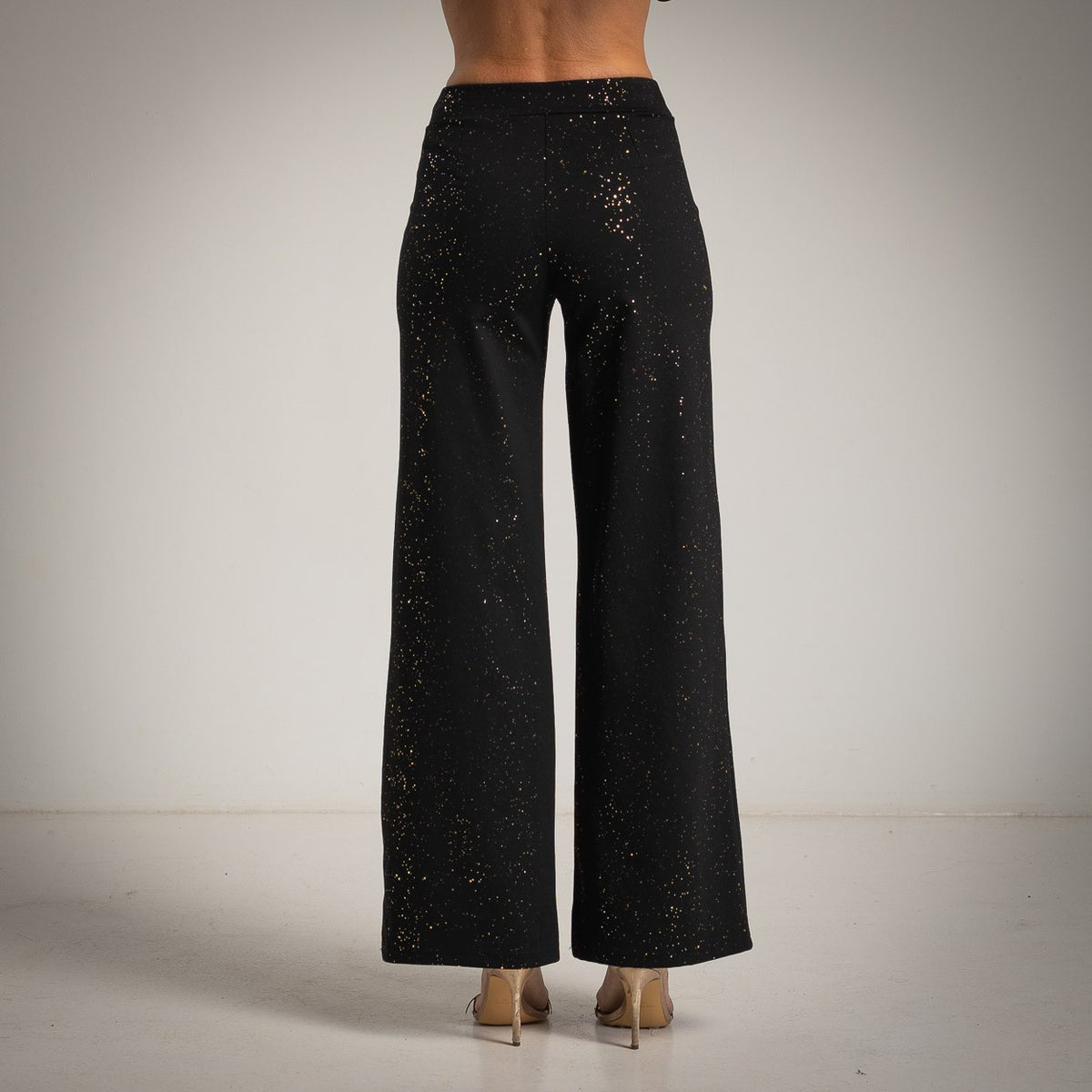 Black high-rise flared pants with scattered golden glitter foil - back view