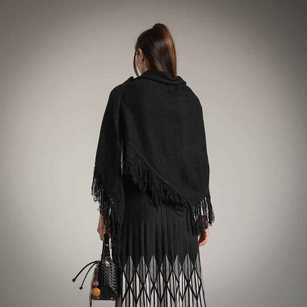Black fringed knit shawl worn over pleated skirt – back view