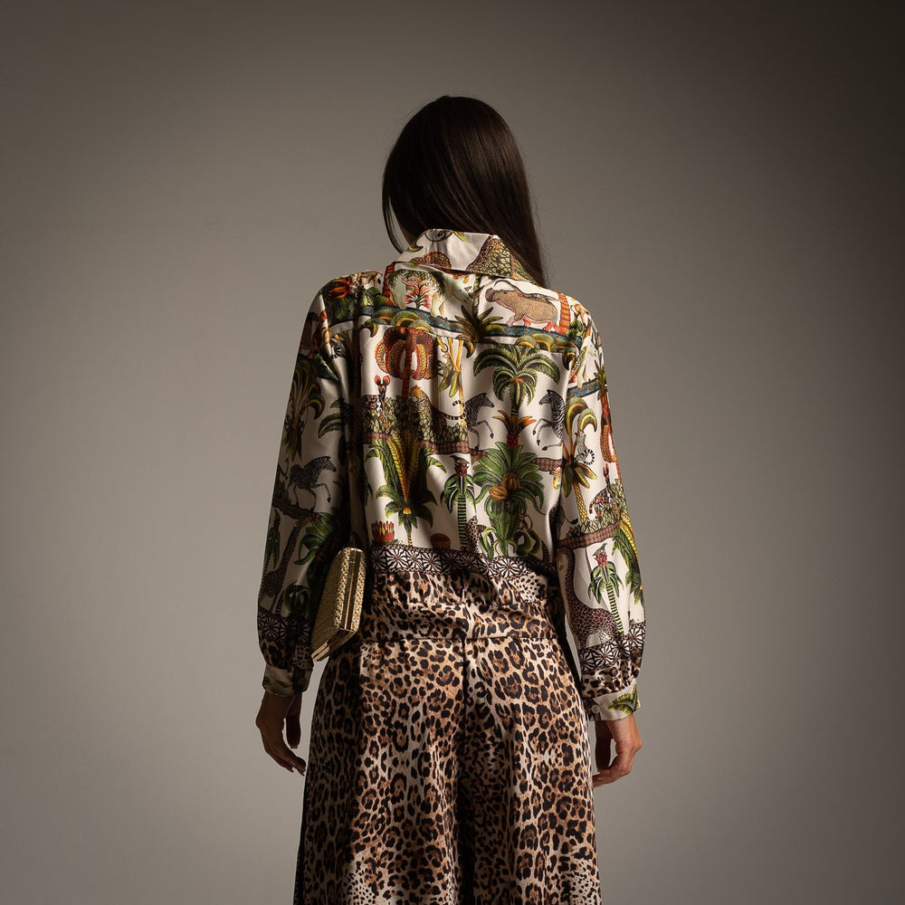 Back view of ivory white safari print shirt with tropical animal and palm tree design paired with leopard print trousers