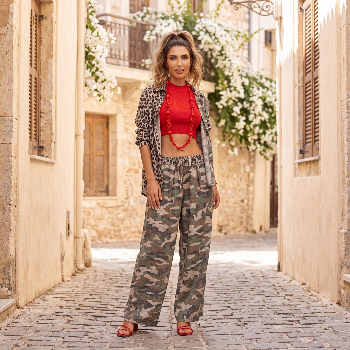 Woman wearing the Mila camouflage wide-leg pants styled with a red knit top and leopard-print shirt