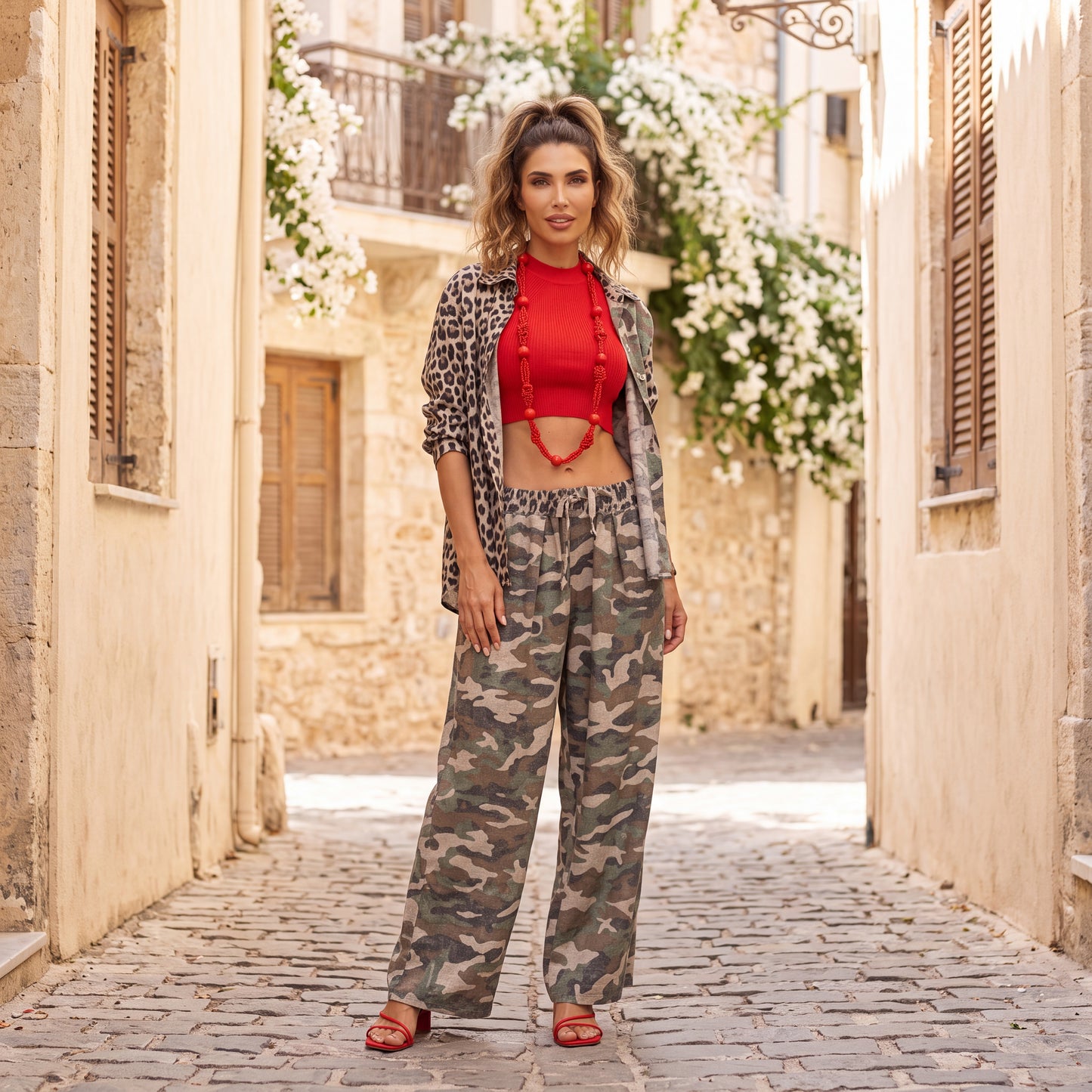 Woman wearing the Mila camouflage wide-leg pants styled with a red knit top and leopard-print shirt