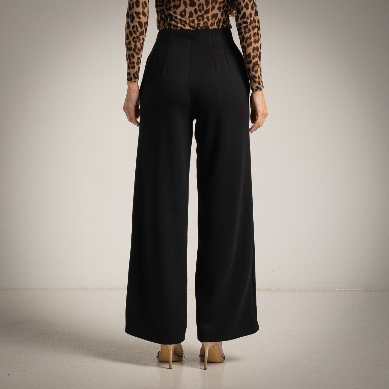 Black high-waisted flared trousers with a pressed centre seam - back view