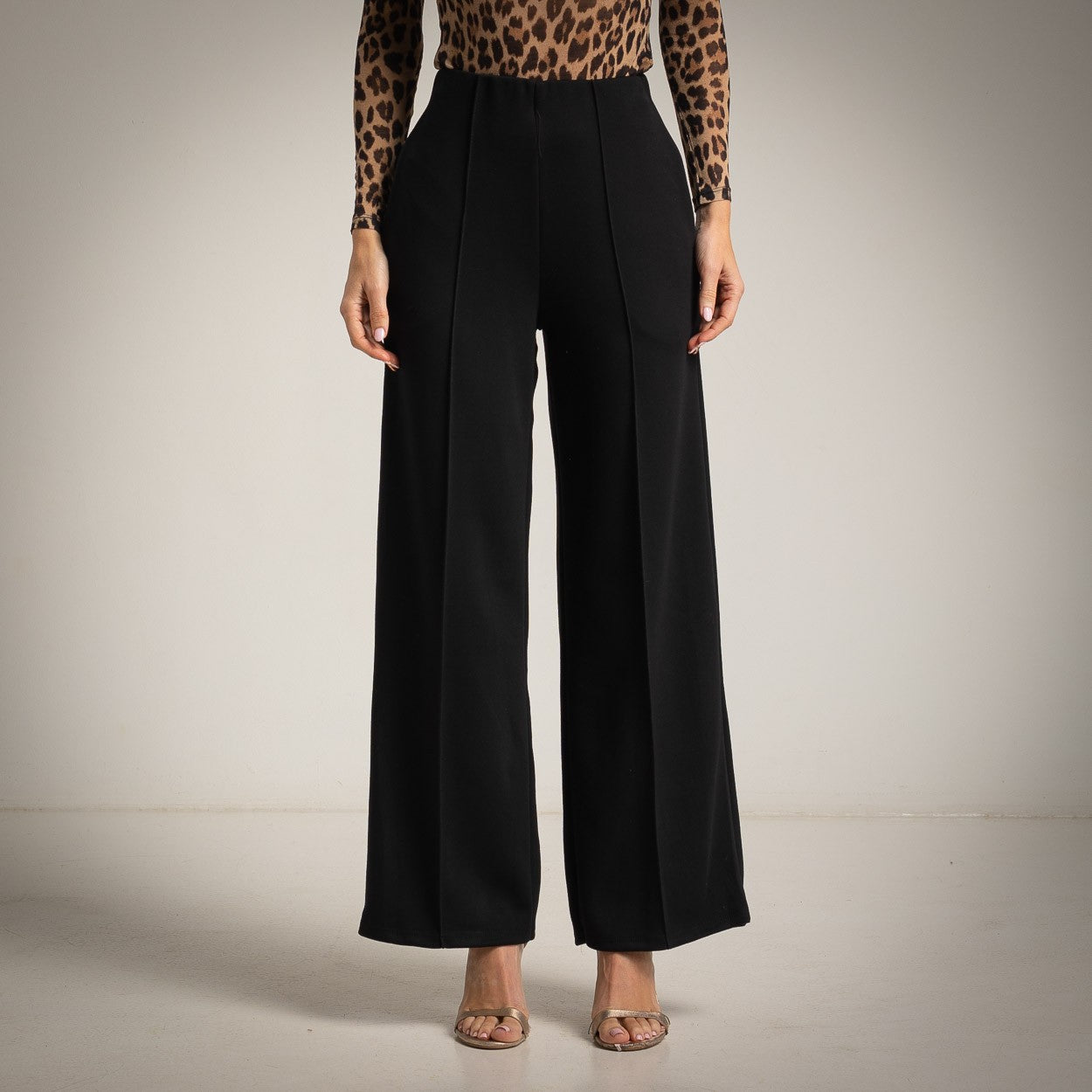Black high-waisted flared trousers with a pressed centre seam - front view