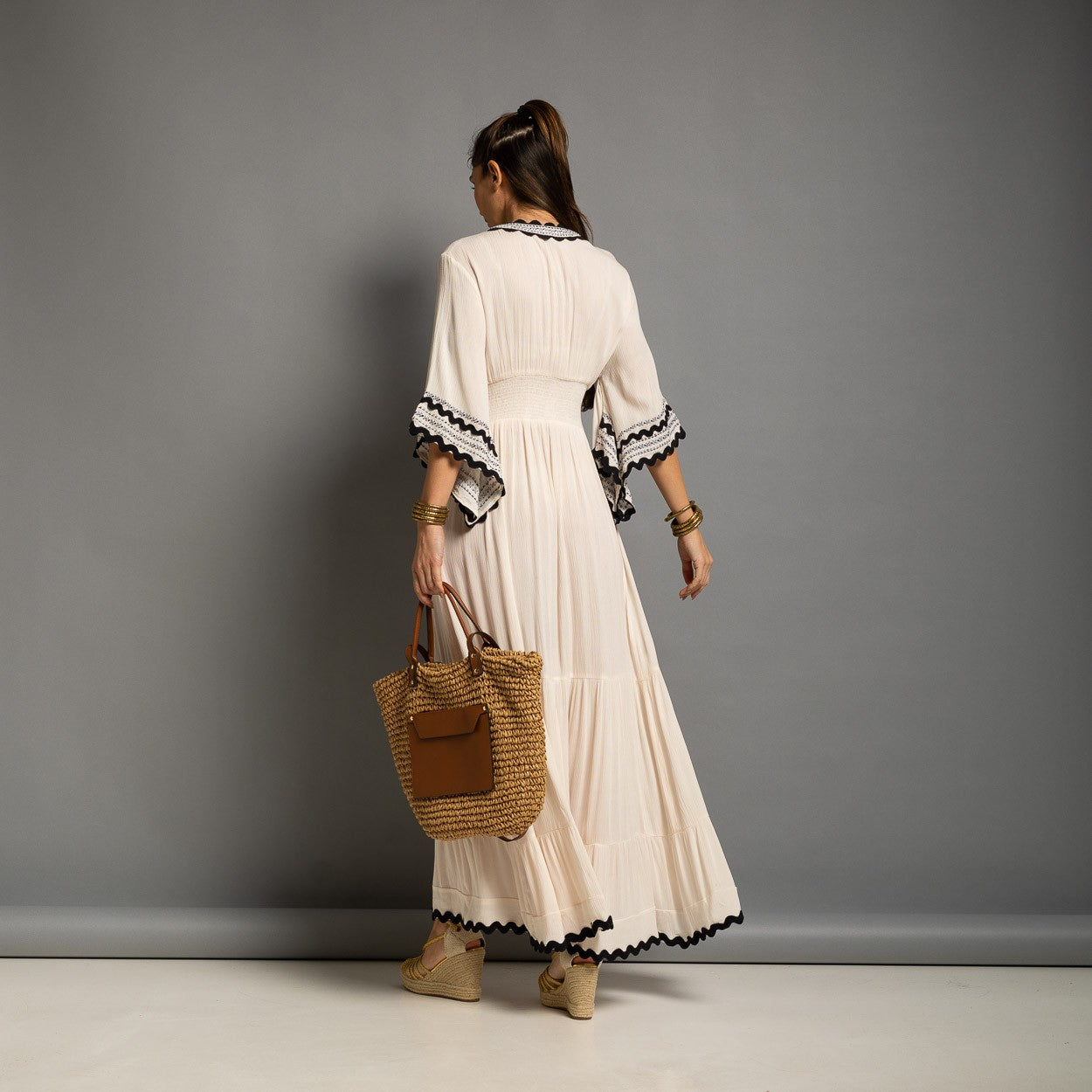 Back view of an elegant ivory boho maxi dress with a smocked waist and flowing tiered skirt.