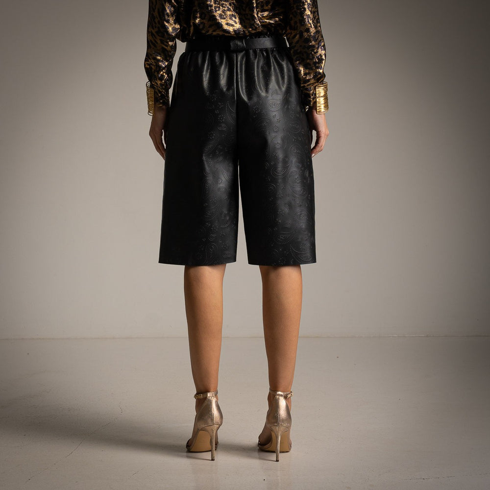 Back view of embossed black faux leather Bermuda shorts with elegant paisley texture.