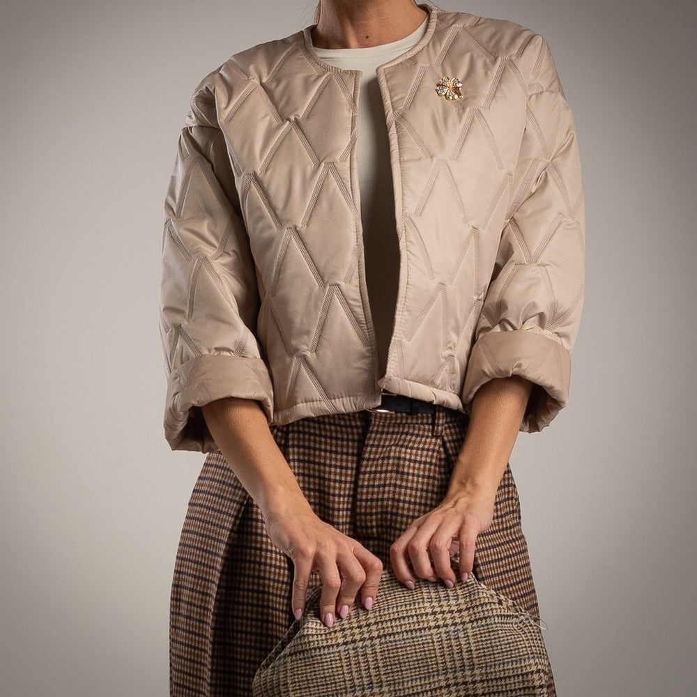 Beige quilted jacket with clover brooch front view