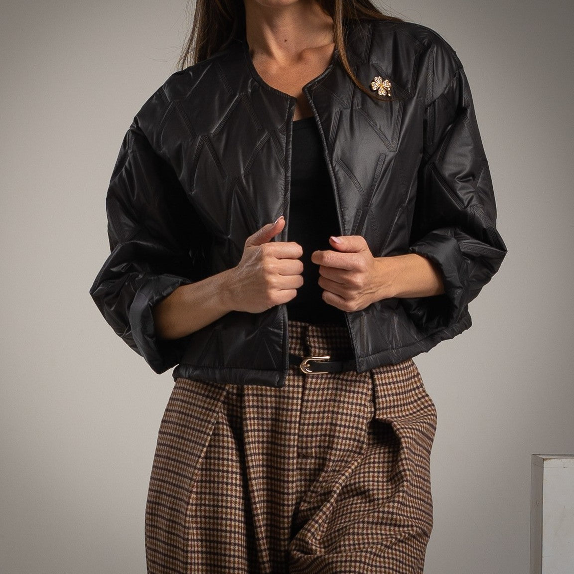 Black quilted jacket with clover brooch front view