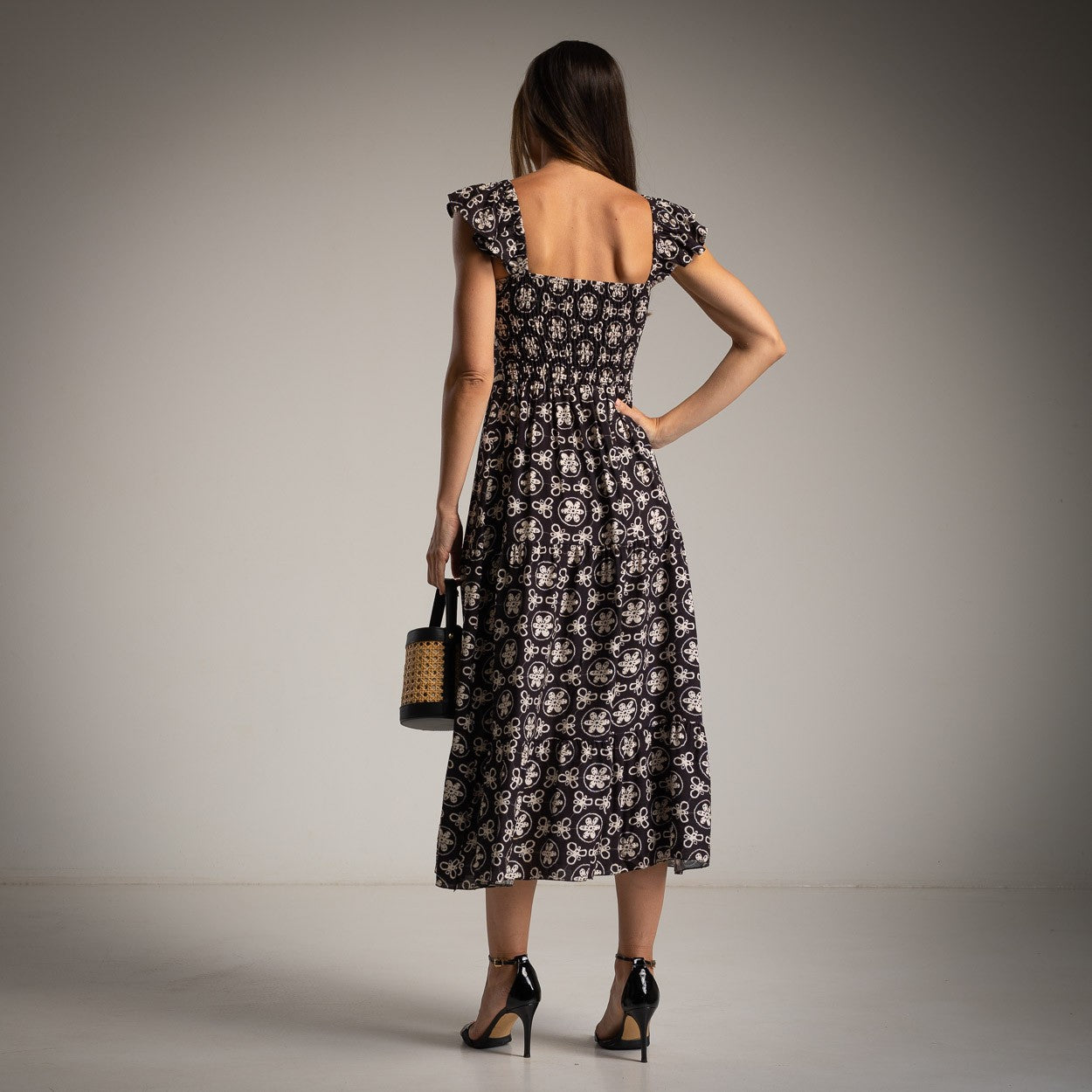 Back view of MARIΓIOÚ retro midi dress in black with ruffle straps and smocked panel