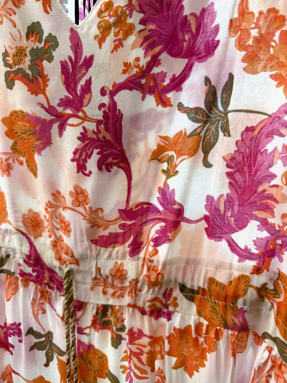 Close-up of the pink and orange floral print with tassel tie detail on the Santorini Bloom tunic