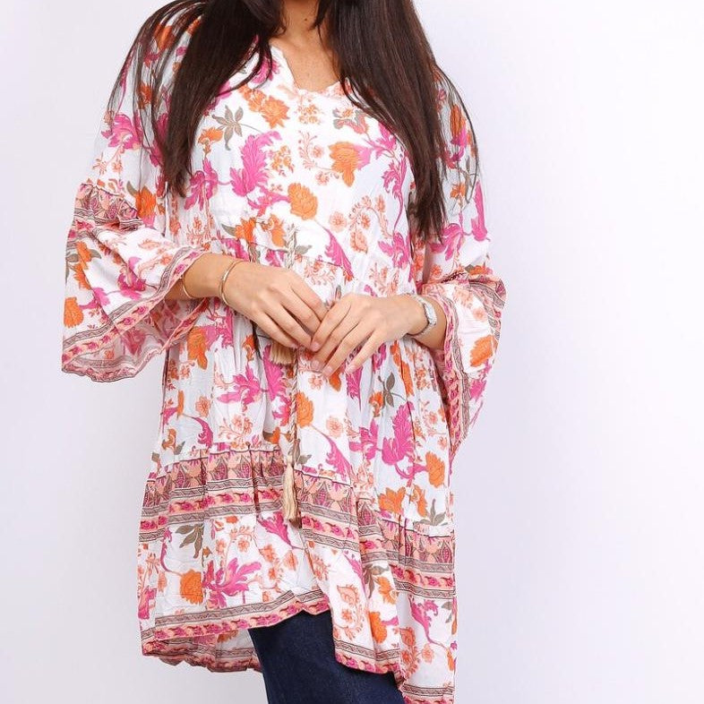 Woman wearing a white floral boho tunic with pink and orange print and 3/4 sleeves.