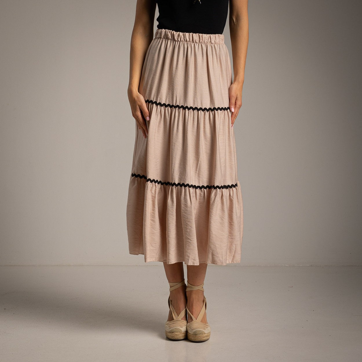 Elegant soft sand beige tiered midi skirt with black trim front view