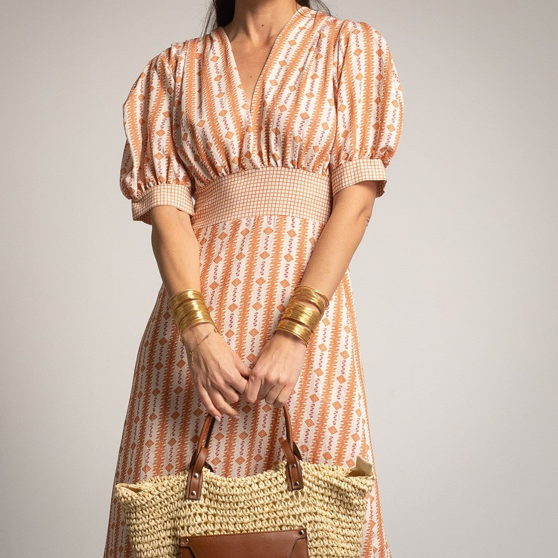 Close-up of MARIΓIOÚ teja V-neck puff sleeve midi dress with smocked waist detail