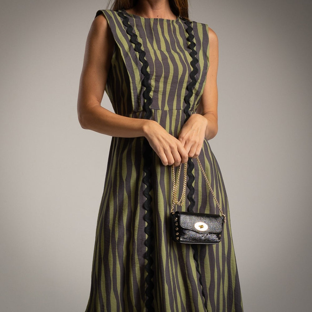 Detail view of MARIΓIOÚ striped midi dress in green and black camou style, highlighting vertical stripe pattern and decorative trim