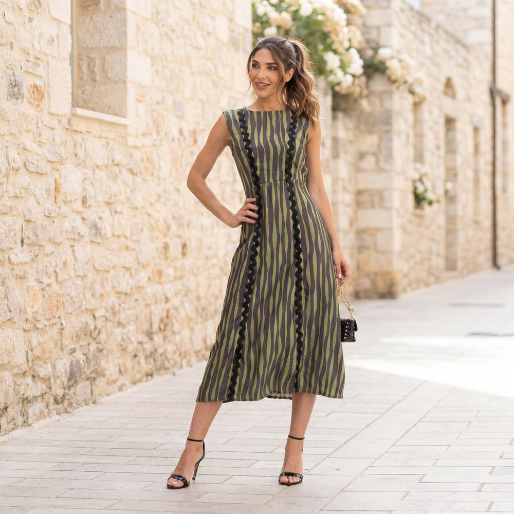 MARIΓIOÚ striped midi dress in green and black camou vibes, styled in a Mediterranean stone alley with black heels and mini chain bag