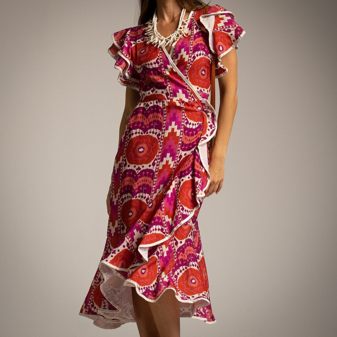 Close-up of Sunset Fuchsia Mediterranean wrap dress with ruffle details