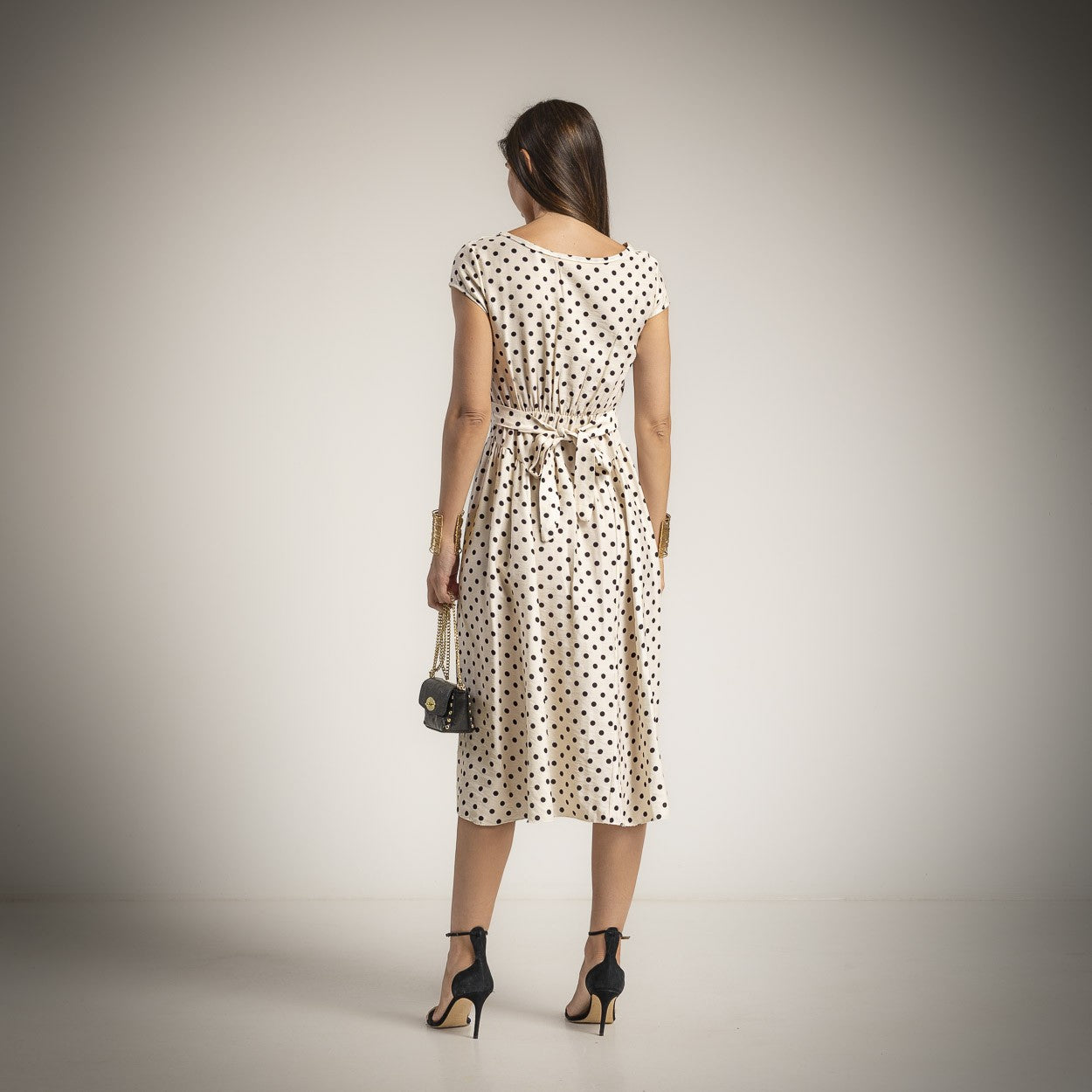 Back view of elegant polka dot midi dress in vanilla beige with adjustable waist detail and flowing skirt