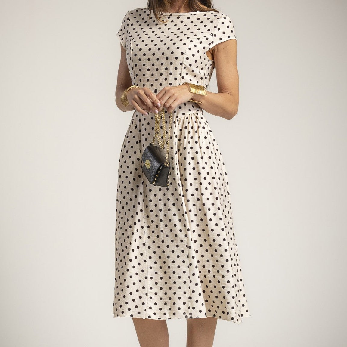 Front view of elegant vanilla beige polka dot midi dress with feminine silhouette and black dot print