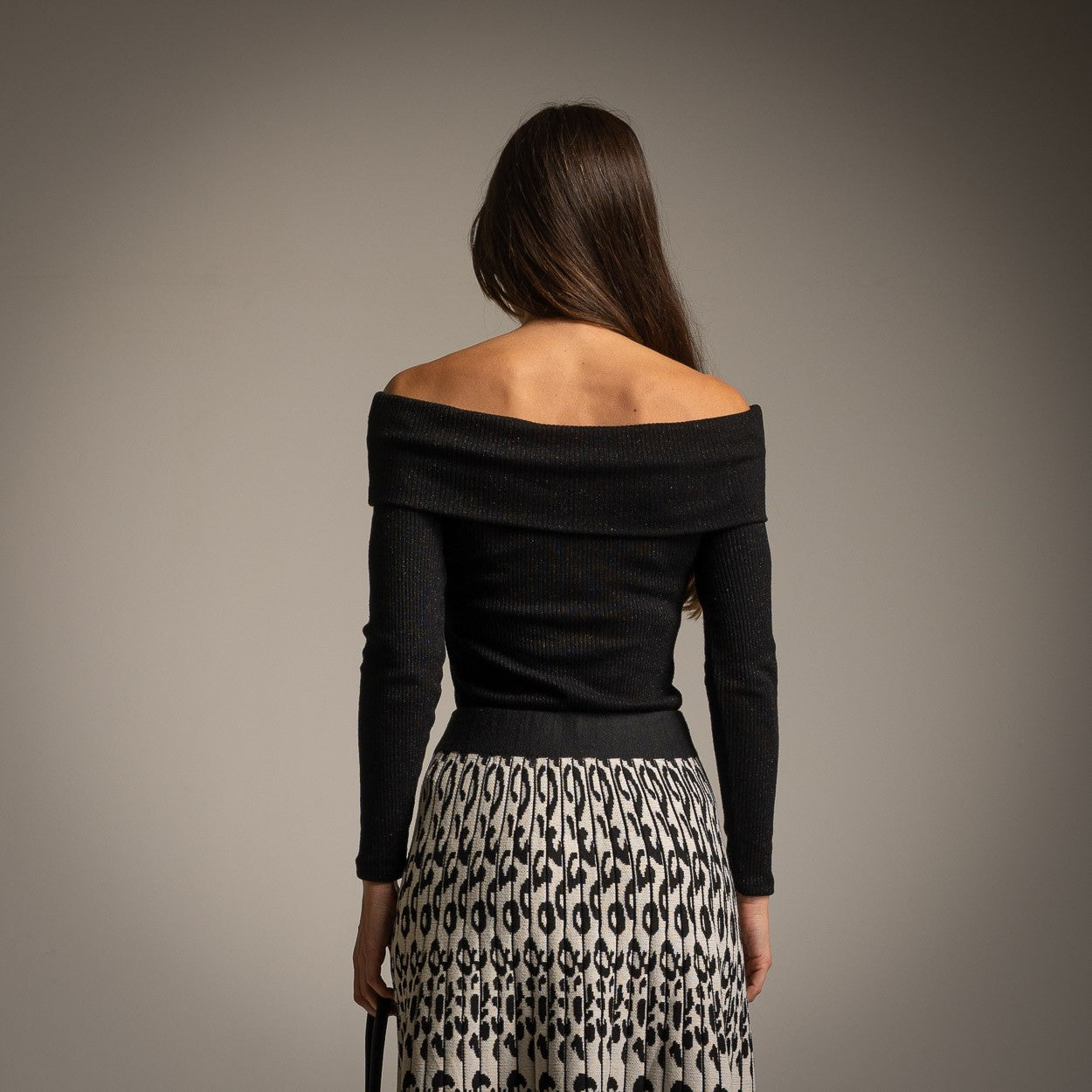 Black off-shoulder shimmer knit sweater styled with pleated skirt