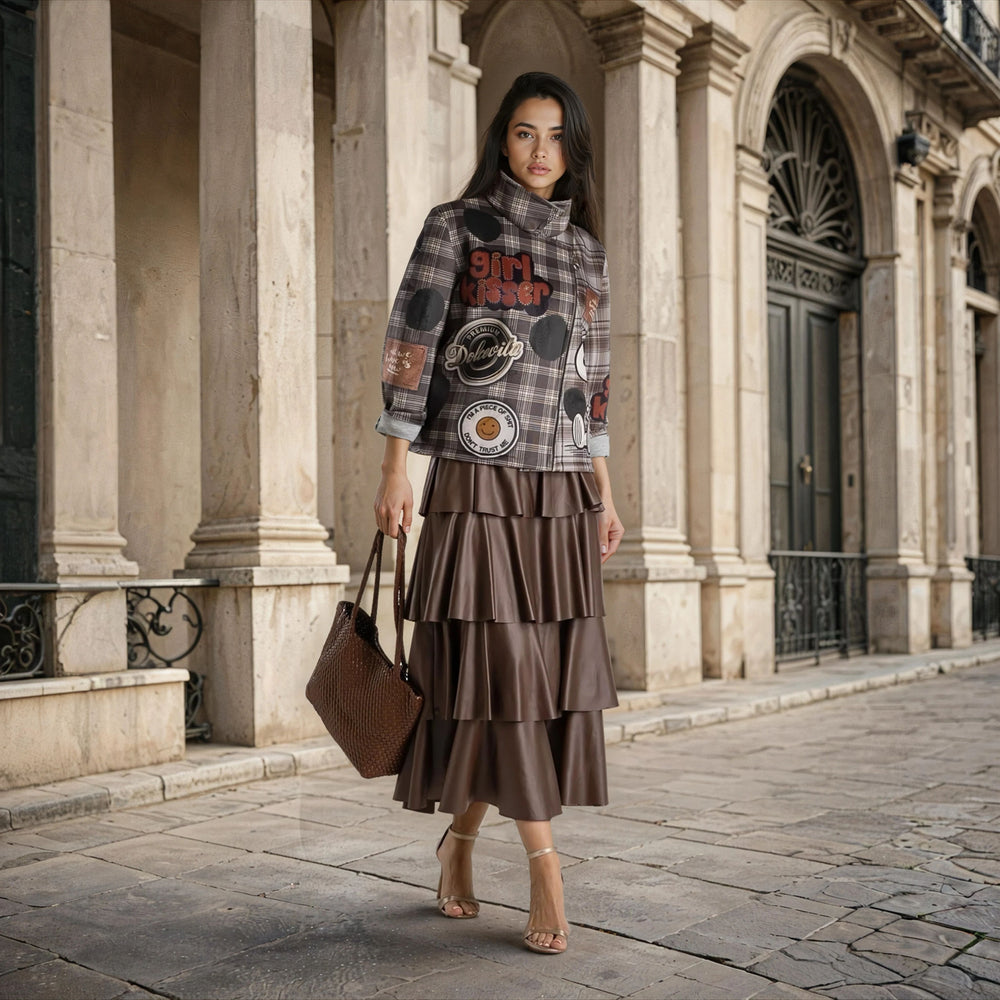 Model wearing MARIΓIOÚ Snoopy plaid neoprene jacket and brown tiered skirt outdoors.